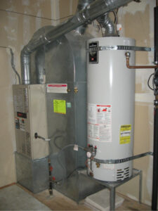 Gray furnace unit with ductwork connected to white cylindrical water heater in basement with safety labels visible.